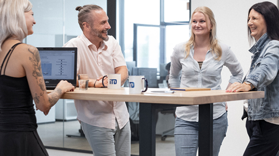 A diverse group of individuals standing around a table engaged in a discussion