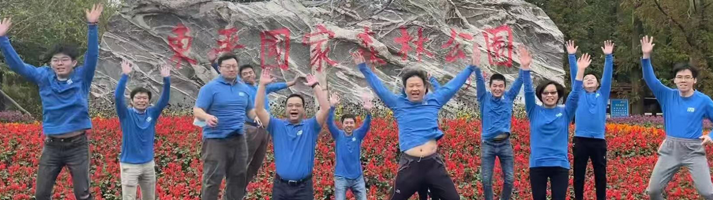 Group of people in blue iTD shirts jumping in front of large rock