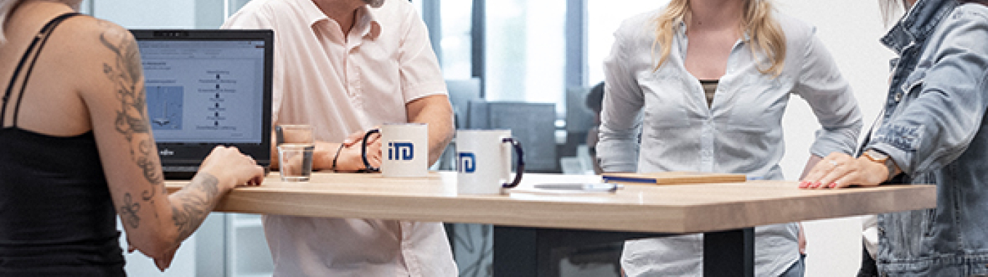 A diverse group of individuals standing around a table engaged in a discussion