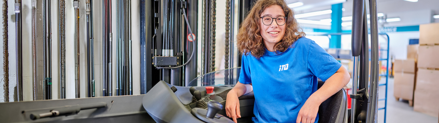 A woman in an iTD blue shirt sitting on a forklift